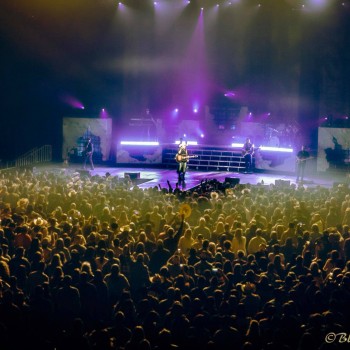 View of the stage at a concert from behind the crowd.