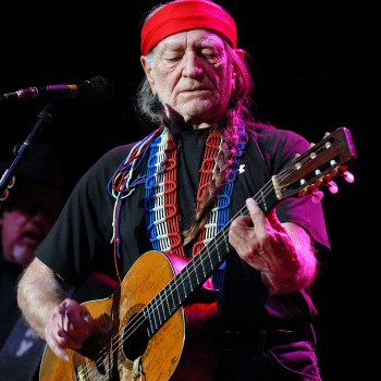 Willie Nelson singing and playing the guitar.